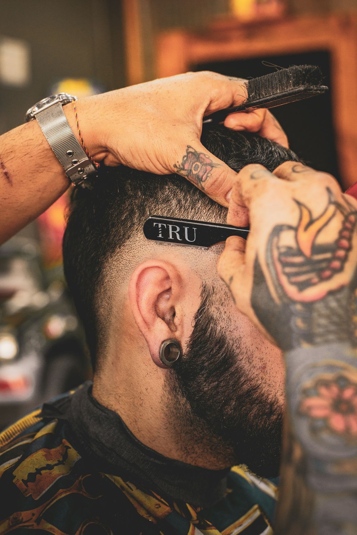 Barber working a clean line-up with a comb and clippers