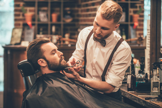 Traditional barber working on a client's beard